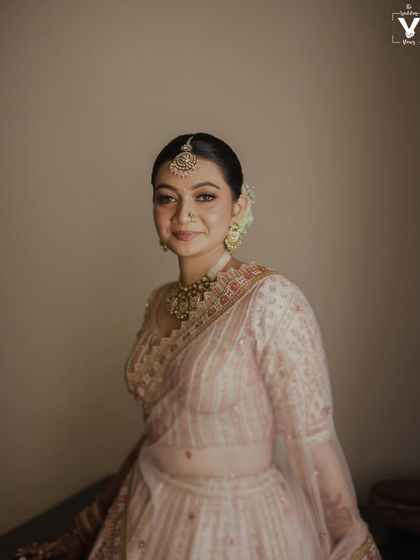A beautiful portrait of the bride in her elegant light pink lehenga. Her gentle smile and the soft, natural light create a look of timeless grace and serenity.