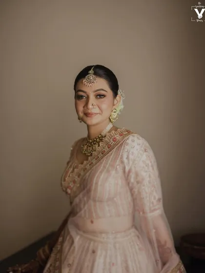 A beautiful portrait of the bride in her elegant light pink lehenga. Her gentle smile and the soft, natural light create a look of timeless grace and serenity.