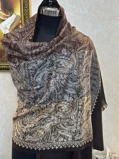 A beautiful Kashmir pashmina with intricate paisley embroidery, draped on a mannequin. The colour gradient from brown to silver is very elegant.