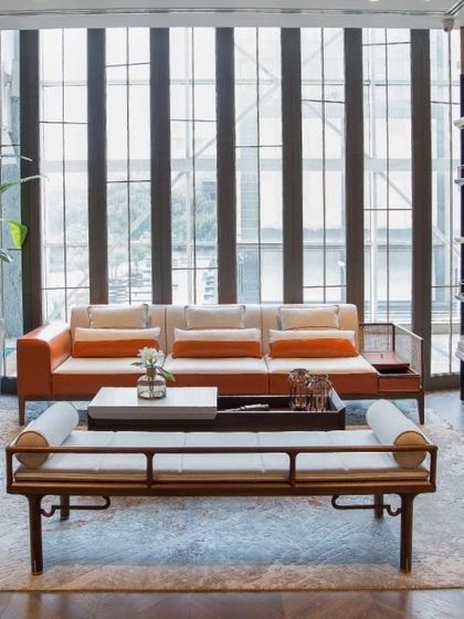 We balanced hard and soft materials in this airy living room. The modular sofa features a wood frame with cane work, while the floor-to-ceiling bookshelf is crafted from black cane and wood for a linear, lightweight feel.
