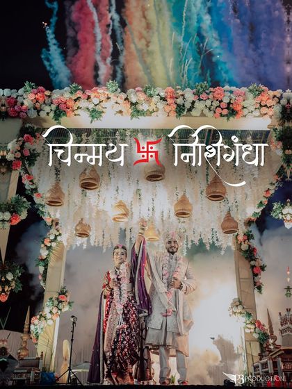 The couple stands under a beautiful mandap during their pheras, with colorful smoke effects creating a vibrant and divine atmosphere.