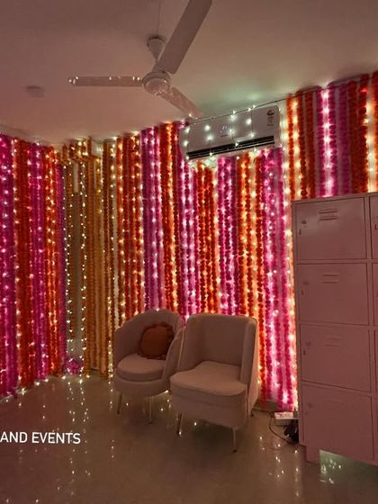A full view of my popular marigold and fairy light wall decoration. The vertical strings of pink, orange, and yellow flowers mixed with lights create a dense, vibrant backdrop that instantly makes any room feel festive.