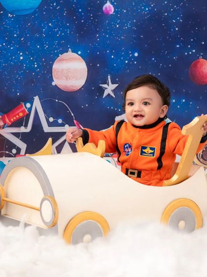 A happy astronaut ready for his first birthday adventure. The '1' prop and his big smile mark the special occasion.