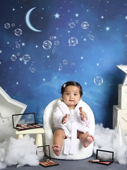 A spa day for baby. This little one is wearing a bathrobe and surrounded by makeup palettes in this playful and unique variation of our starry night theme.