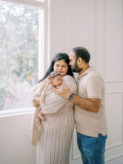 The whole family together in a warm embrace by the window. This photo captures the complete circle of love around the new baby.