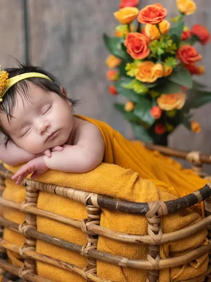 The rich yellow wrap and rustic basket create a warm, earthy feel for this newborn portrait.
