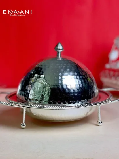 This cloche-style serving dish features small feet and handles, making it easy to carry and present. The hammered texture adds a timeless, handcrafted feel.