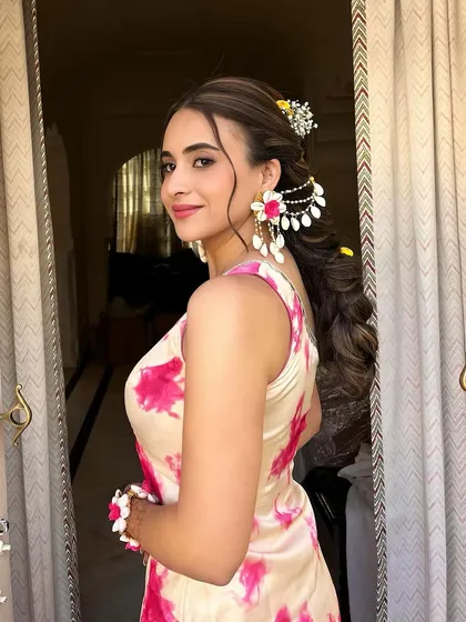 A beautiful client with a half-up style and soft waves, adorned with a floral hair accessory for her Haldi ceremony.