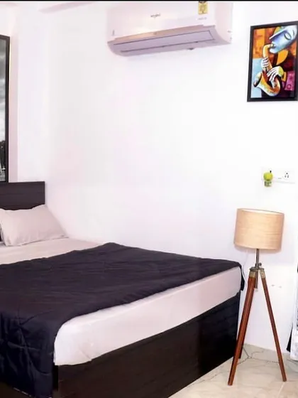 A clean and simple bedroom arrangement, showing the comfortable bed, AC unit, and ambient lighting, ready for your stay.