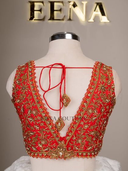 This sleeveless red blouse is perfect for a bold bridal statement. It features a deep V-neckline and is heavily embellished with intricate gold floral zardozi work, creating a rich and luxurious feel.