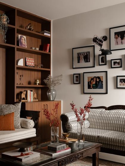 This view shows how the custom-built TV unit with its integrated seating nook connects to the rest of the living area, including the family's cherished gallery wall. By refurbishing their existing sofa, we preserved memories while giving the space a fresh, cohesive look.