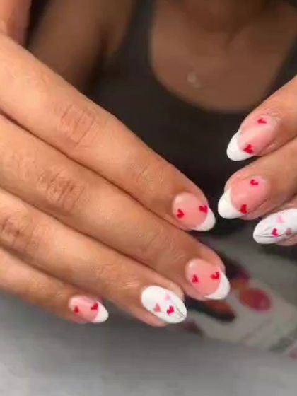 A sweet and romantic take on a French manicure. This set features classic white tips with tiny, hand-painted red hearts scattered across the nail.