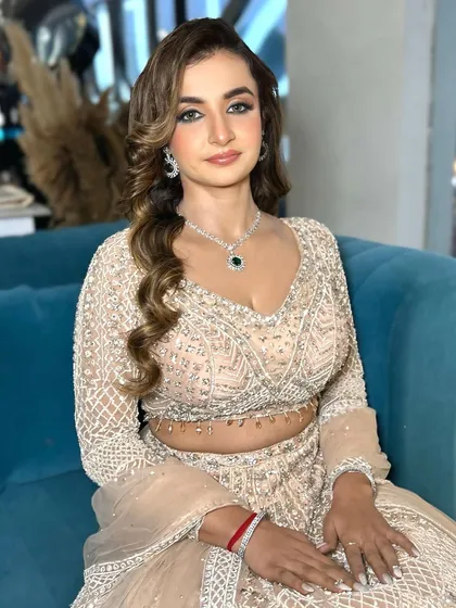 A candid shot of Vaishali looking radiant on a blue couch. The lighting highlights the dewy finish of her skin.