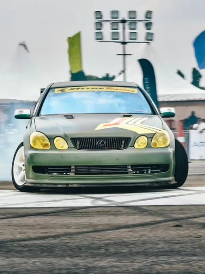 A custom Lexus drift car going sideways, tires smoking, in front of the packed spectator area. We bring in top drifters to put on a world-class show.