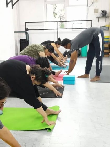 An evening class working on forward folds and hamstring stretches with instructor guidance.