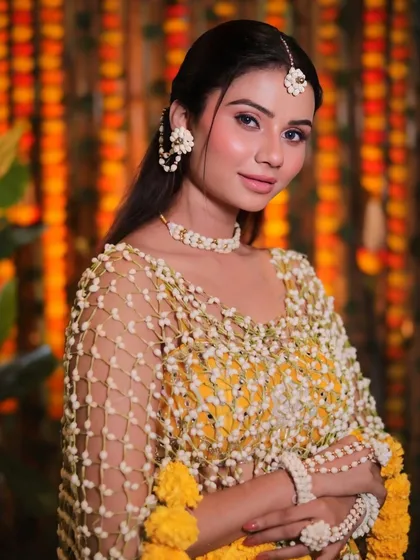 A close-up of the recreated Haldi look. The makeup is minimal and fresh, with a focus on skin that looks healthy and luminous, complemented by delicate floral jewelry.