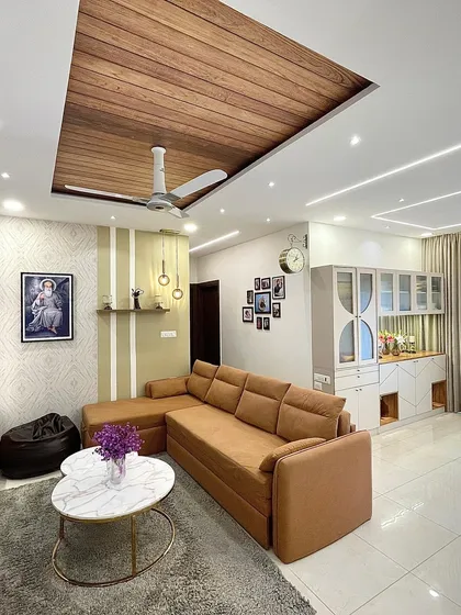 This living room is a perfect example of modern elegance. I combined a comfortable mustard sofa with a striking wooden-paneled false ceiling and unique wall textures to create a space that is both stylish and welcoming.