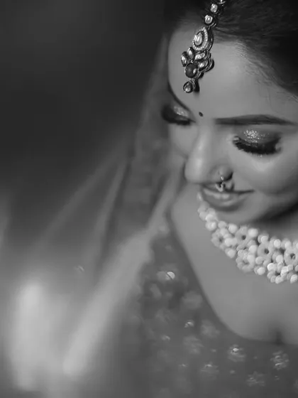A soft, artistic close-up of the bride. This black and white portrait beautifully highlights her intricate jewelry, makeup, and serene expression on her wedding day.