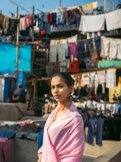 The layers of laundry create a textured, almost abstract background, making the model in her simple pink saree stand out beautifully.