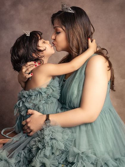 A tender kiss between mother and daughter, both wearing matching crowns. This intimate moment feels like a scene from a storybook.