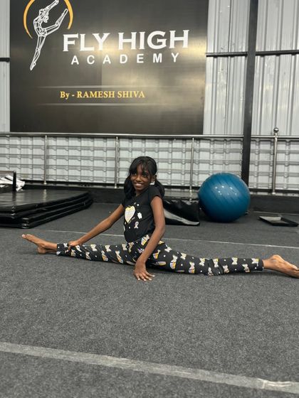 A young student proudly shows off her full split, a result of consistent practice in our flexibility drills.