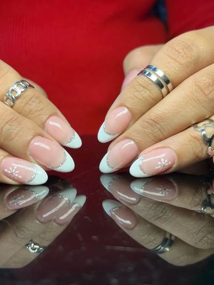 A winter-themed French manicure with frosty white glitter tips and a delicate hand-painted snowflake on an accent nail.