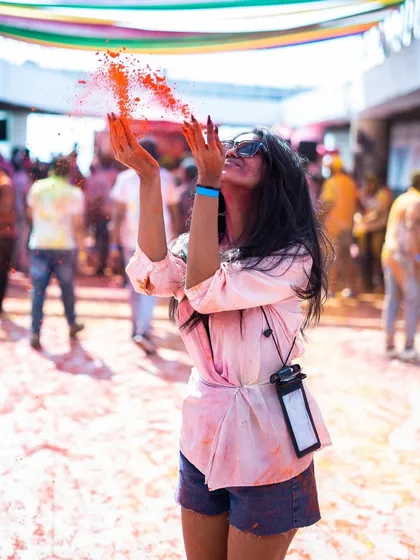 A candid shot of a guest tossing colored powder in the air at Holi Utsav. We use organic and safe colors to ensure a worry-free celebration for everyone.