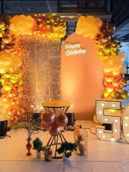 I also create grand backdrops for milestone celebrations like a 50th birthday party. This setup includes a shimmering sequin wall, large marquee numbers, and a stylish balloon arch in a sophisticated gold and bronze color scheme. It serves as a perfect photo corner for guests to capture memories.