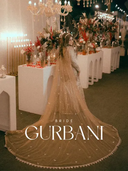 A stunning full-length portrait of the bride, Gurbani, showcasing the magnificent trail of her golden gown against the elegant reception decor.