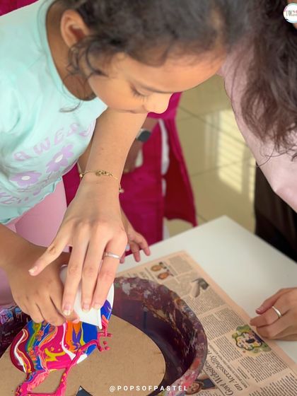 A participant carefully tilts her canvas to guide the flow of paint, an essential step in creating the final look of a fluid art piece.