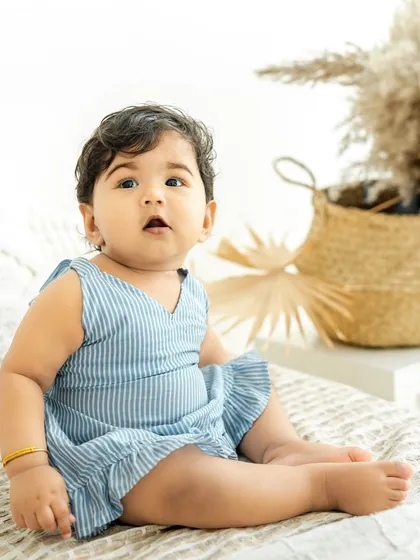 This sweet baby girl sits contentedly in a lovely blue striped dress, a perfect portrait from a warm and loving family session.