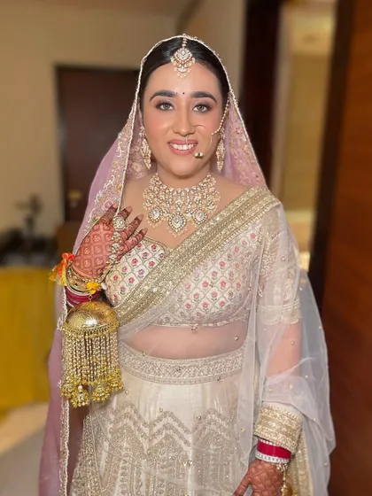 A full-length view of a bride in her elegant white and gold lehenga. Her polki necklace and traditional kalire add a timeless grace to her modern bridal look.