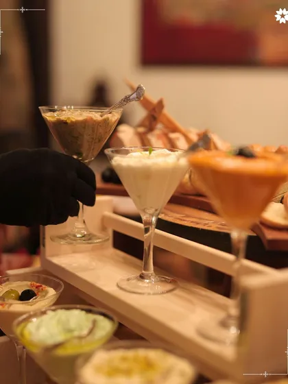 A selection of gourmet dips served in martini glasses. This creative presentation elevates a simple appetiser, adding a touch of elegance to your home catering spread.