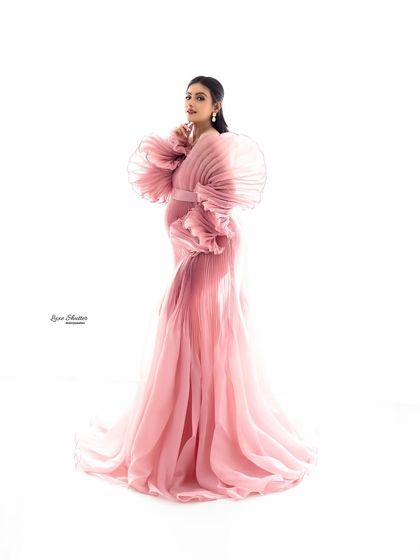 A graceful pose in a stunning pink gown, highlighting the intricate pleats and statement sleeves.