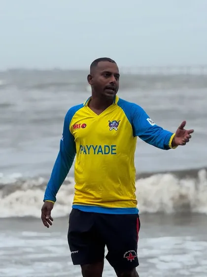 A coach directs players during a complex fielding drill on the beach. Clear communication and strategy are just as important as physical skill.