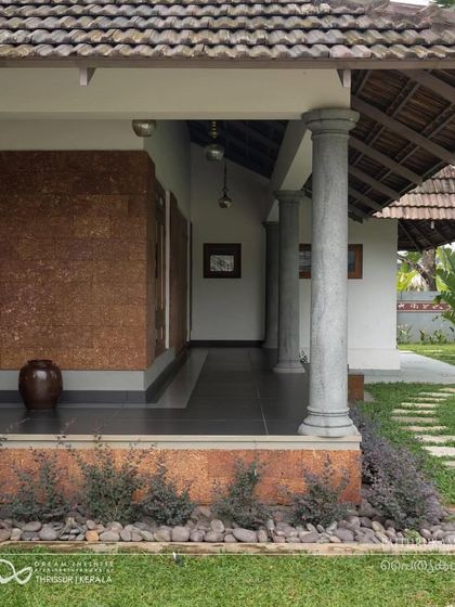 The 'Paithrukam' project by Dream Infinite Studio showcases traditional Kerala architecture with its sloping tiled roof, stone pillars, and inviting verandah.