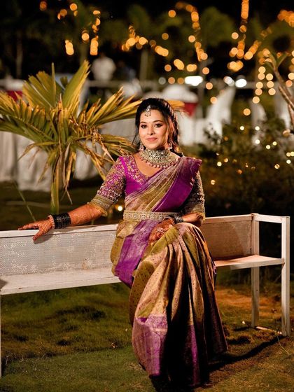 My dear client Spoorthi looks like a doll in this classic South Indian bridal look. Her rich purple and gold Kanchipuram saree is paired with a pink blouse featuring delicate hand embroidery, perfect for her wedding ceremony.