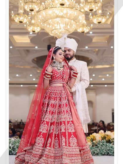 A classic couple pose under a magnificent chandelier. The lighting highlights the bride's glowing makeup.
