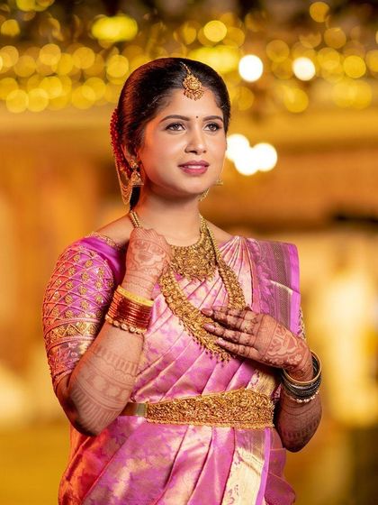 A close-up of the bride's happy face, her hands framing her beautiful jewelry and showcasing the rich mehendi stain.