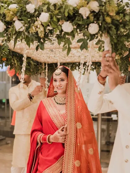 The bride's entrance. The sleek bun and gajra, seen under the phoolon ki chadar, create an iconic and timeless bridal image.