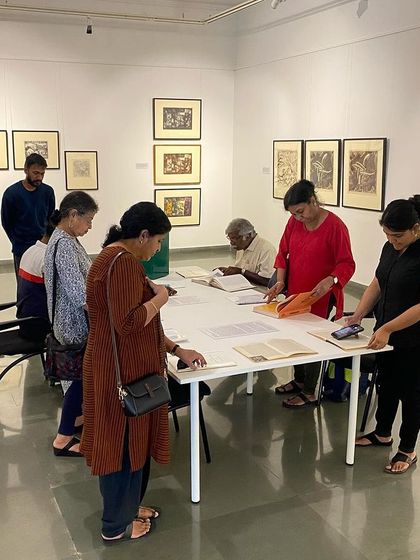 More visitors exploring the archival materials at the library table.