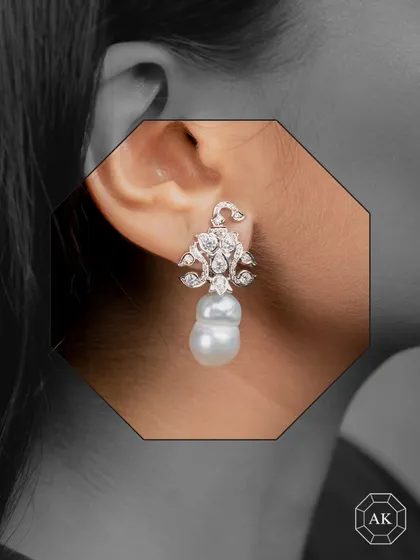 These paisley-style English earrings are crafted in 18K gold, featuring a stunning baroque South Sea pearl drop enhanced by natural round diamonds.