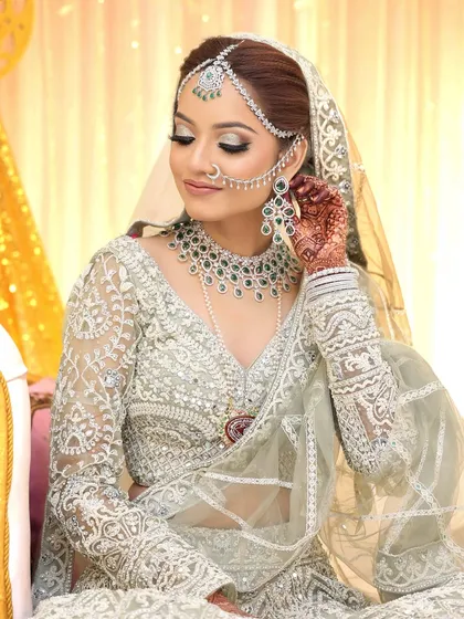 An ethereal Muslim bride wearing a stunning diamond and emerald jewellery set. The intricate nath attached to the hair is a beautiful, traditional touch paired with a modern diamond set.