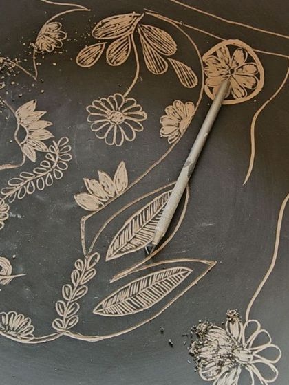 The sgraffito process in action. Here, I'm carving through a layer of black slip to reveal the light clay underneath, creating the design for my rabbit plate.