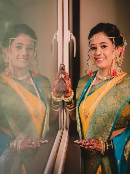 A creative shot using reflections. The bride's traditional look is captured beautifully, showcasing the elegance of her attire and the soft glow of her makeup.