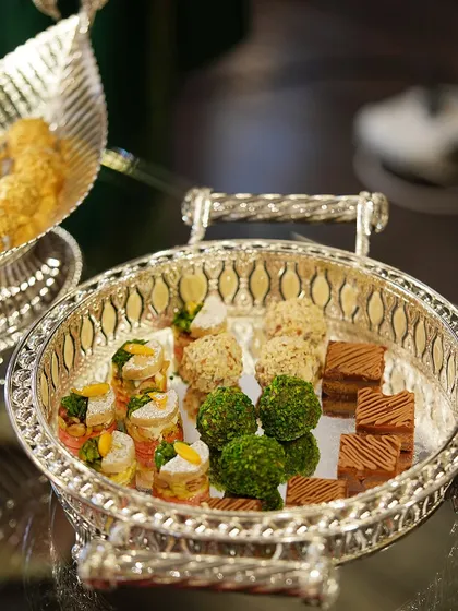 A festive tray adorned with delightful sweets, bringing warmth and celebration to the occasion. The intricate design of the silver-plated tray enhances the presentation.
