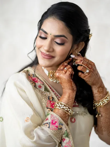 A beautiful, detailed shot of Supriya getting ready. The focus is on her delicate jewelry and the soft, romantic makeup.