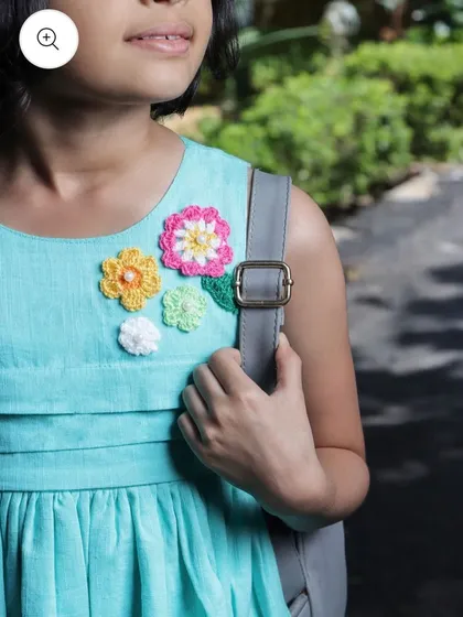 Here you can see a close-up of my custom floral patches on a child's dress. I create these appliqués in various colors and sizes, perfect for adding a playful and personalized touch to kids' clothing.