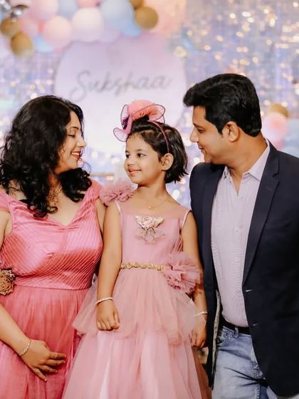 A heartwarming family portrait taken at a 5th birthday party. The parents look lovingly at their daughter, capturing a perfect family moment amidst the celebration.