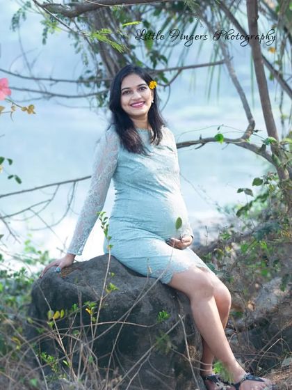 A sweet and natural portrait sitting on a rock. The mom-to-be's gentle smile and the soft blue lace dress create a light and airy feel.